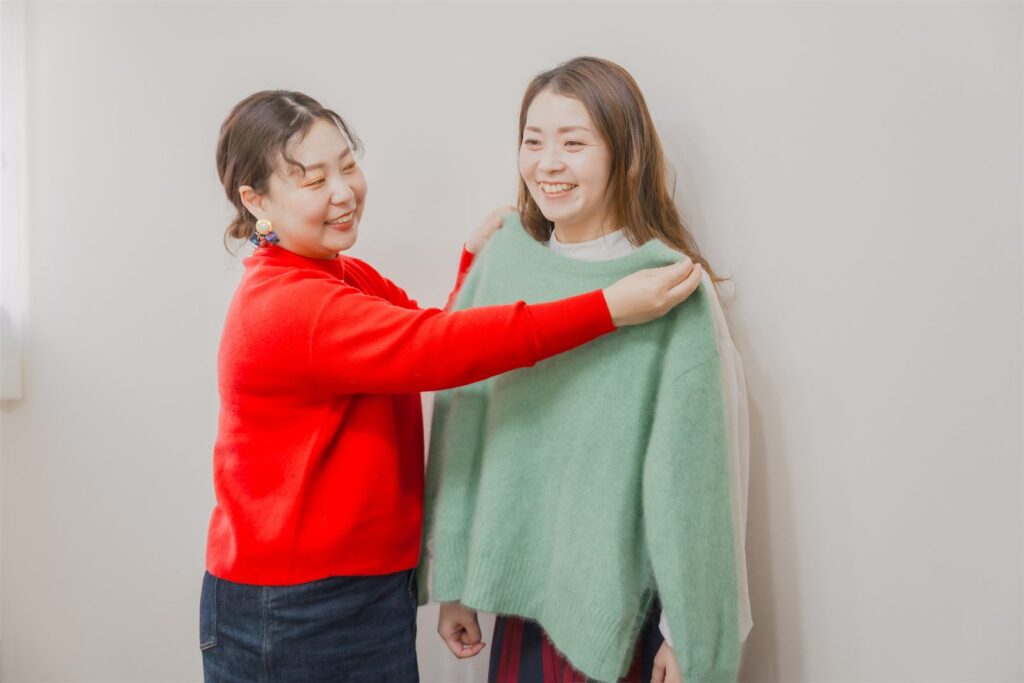 お客様に似合う色のニットを当てて診断している様子